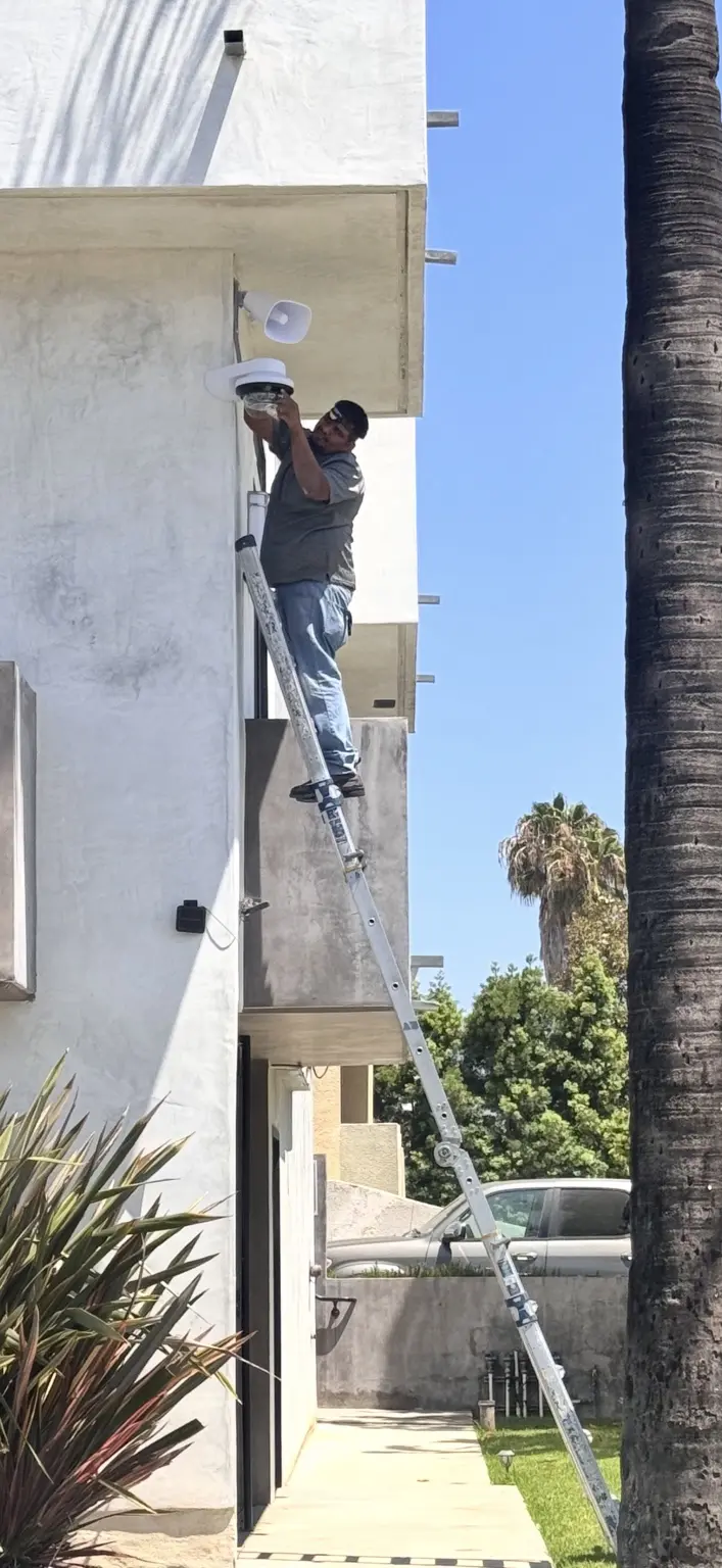 Three Factor Security technician fully visible while installing an exterior camera and PA talk-down speaker — Three Factor Security fieldwork in Los Angeles